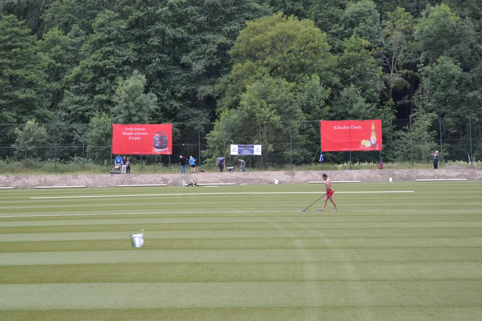 Während die Vereinsmitglieder den Boden neben dem Spielfeld abfrästen, verklebte ein Polytan-Mitarbeiter die Linien Während die Vereinsmitglieder den Boden neben dem Spielfeld abfrästen, verklebte ein Polytan-Mitarbeiter die Linien