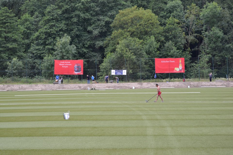 Während die Vereinsmitglieder den Boden neben dem Spielfeld abfrästen, verklebte ein Polytan-Mitarbeiter die Linien Während die Vereinsmitglieder den Boden neben dem Spielfeld abfrästen, verklebte ein Polytan-Mitarbeiter die Linien