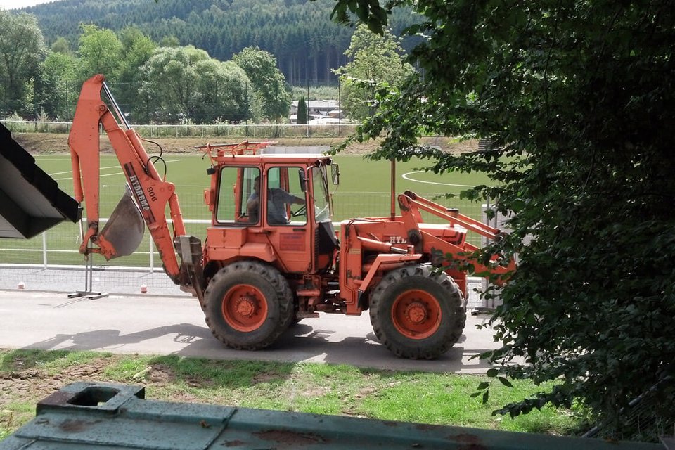 Der Bagger der Firma Hombach beim Auf- und Abfahren vor dem Sportplatz